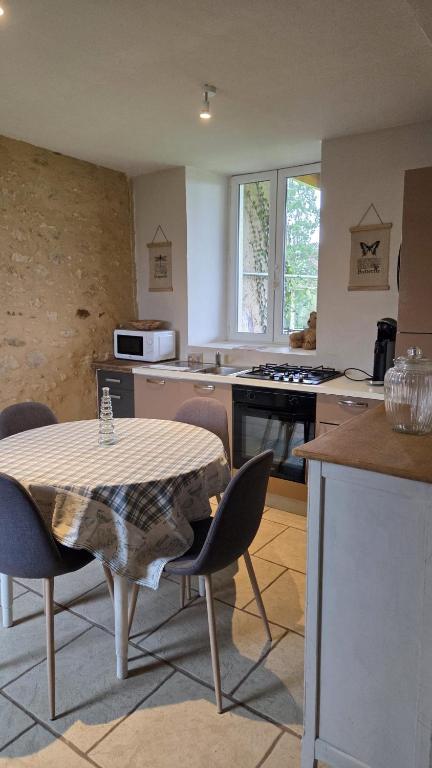 a kitchen with a table and chairs in a kitchen at Petit Gîte à la campagne in Brains-sur-Gée