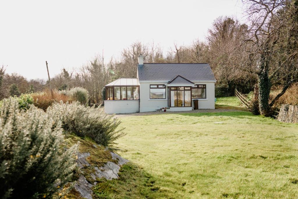 a small white house on a grassy field at The Wild Atlantic Hideaway in Inch