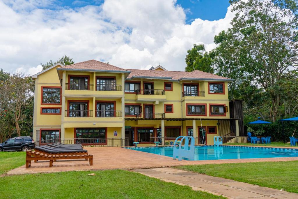 a large yellow house with a swimming pool in front of it at Nyeri Club in Nyeri