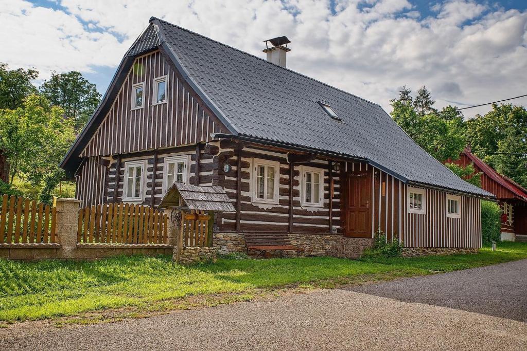 a large wooden house with a fence in front of it at Roprachtická chalupa in Roprachtice