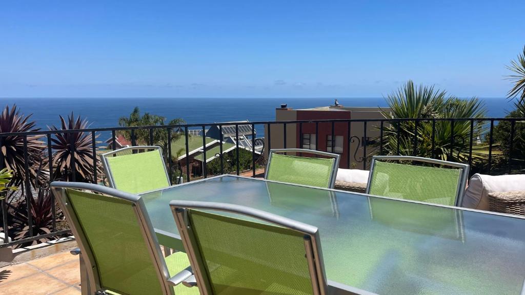 a glass table and chairs on a balcony with the ocean at Apartment Sapphire in Herolds Bay