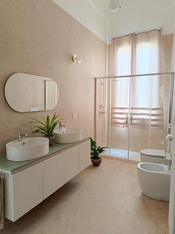 a bathroom with two sinks and a mirror and a shower at Dimora Novecento Lecce in Lecce
