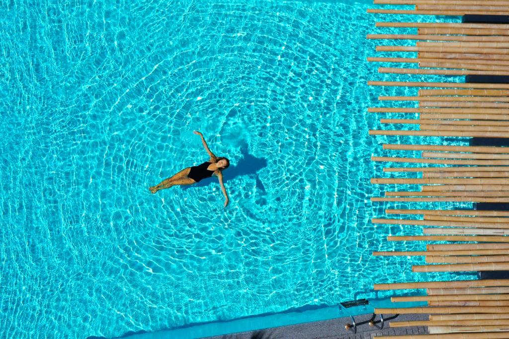 a person swimming in a pool of blue water at Tropicana Hotel Mykonos in Paradise Beach