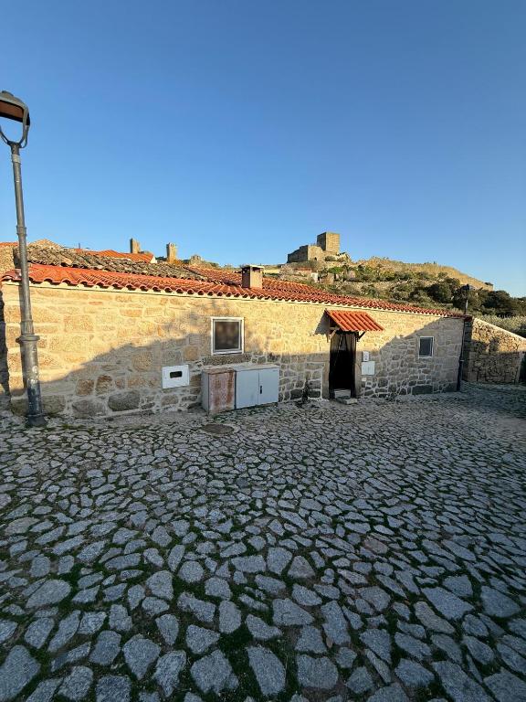 a stone courtyard with a building and a street light at Casa Portela in Marialva