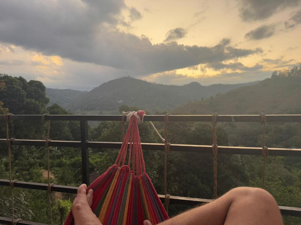 a person sitting on a suspension bridge looking at the mountains at Stag Mountain Resort in Ettampitiya