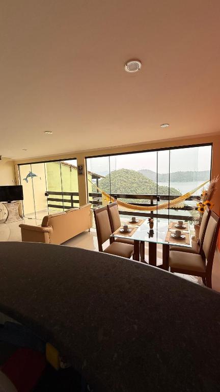 a living room with a table and chairs and a large window at Casa de praia da Michelly in Mangaratiba