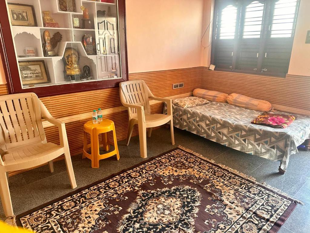 a room with a bed and two chairs and a table at Sri Devi Krupa in Hubli