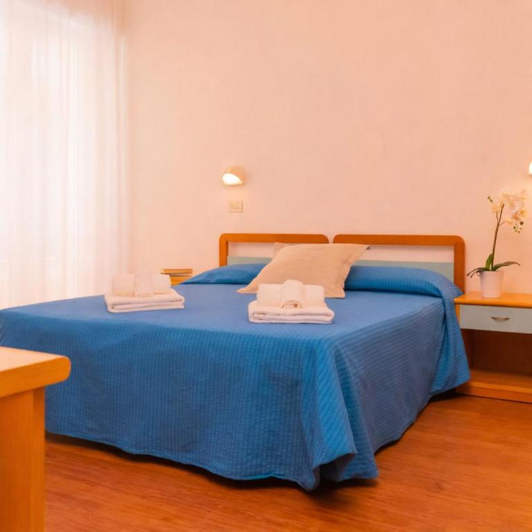 a bedroom with a blue bed with two towels on it at Hotel Merano in Misano Adriatico