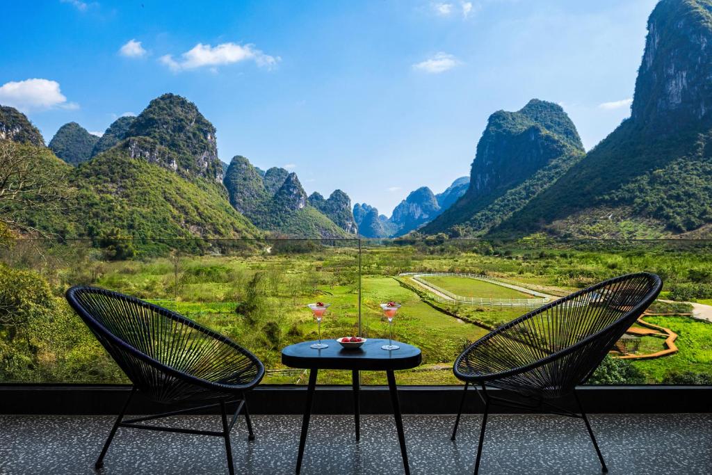 two chairs and a table in front of a mountain view at Hidden Valley Hotel-- New Hotel,A Hidden Gem,Serene Sanctuary,Exclusive Location,Swimming Pool & Cycling Route,Attraction Tickets Serivce in advance,Affordable Luxury,Best Karst Mount View in Yangshuo in Yangshuo