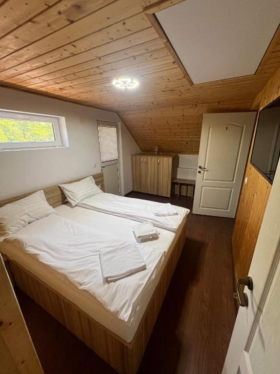 a large bed in a room with a wooden ceiling at Domeniul La Mosie in Slimnic