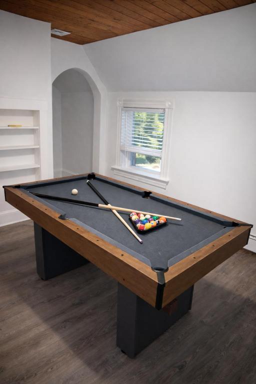 a pool table in a room with two cuesticks at Game Room Fun Extended Stay Friendly in Danielson