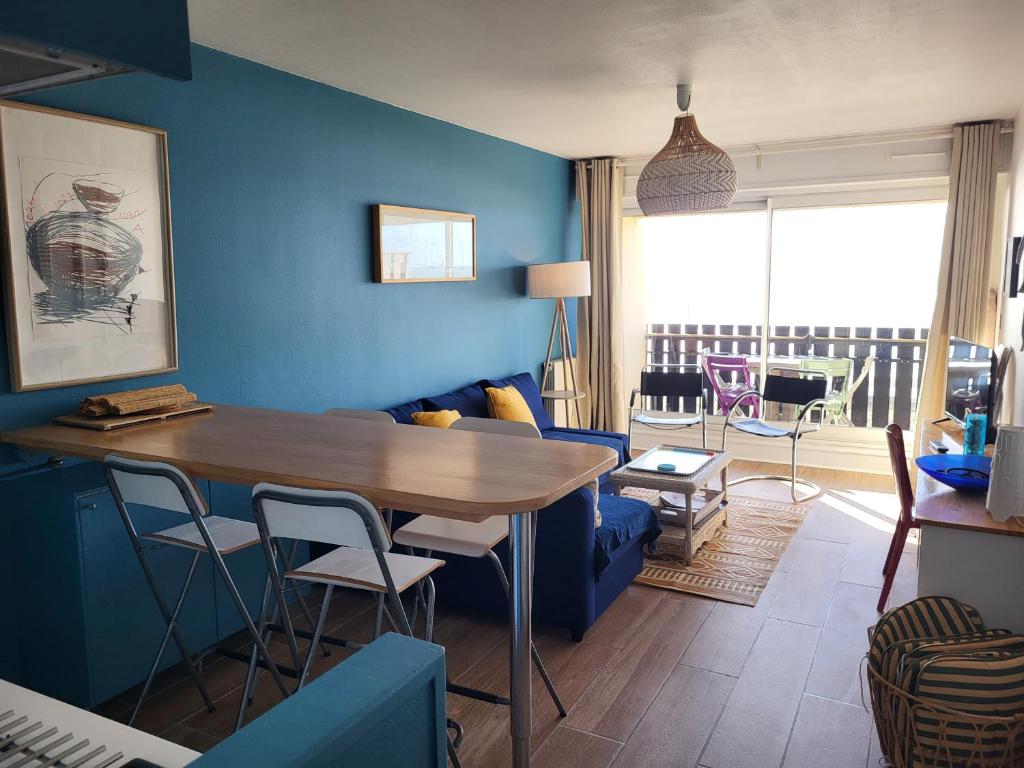 a living room with a table and a blue wall at Ocean View Oceanide in Lacanau-Océan