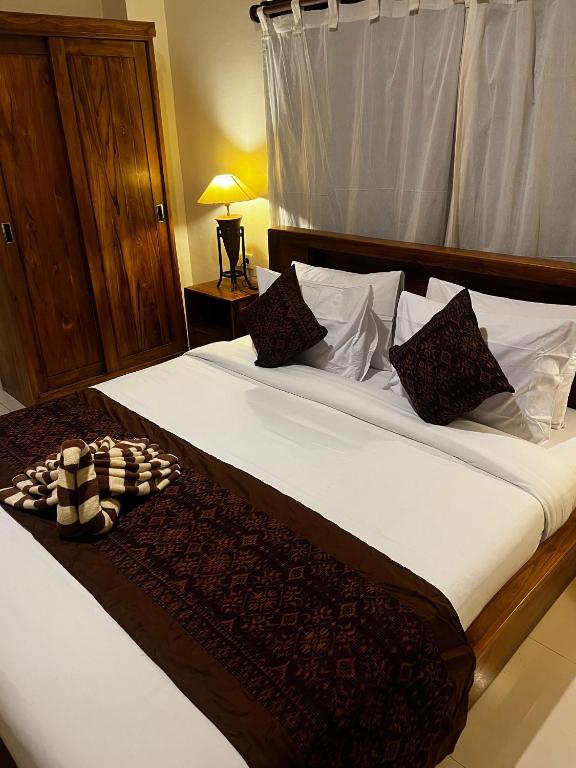 a bedroom with a large bed with white sheets and pillows at Batan Bingin House in Ubud