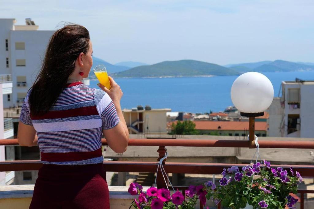 a woman drinking a glass of orange juice on a balcony at The Eden Hotel in Sarandë