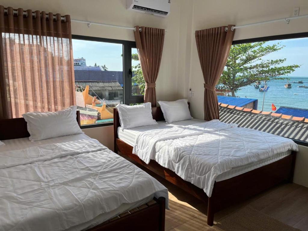 two beds in a room with a view of the water at Sola Hòn Sơn in Lai Sơn