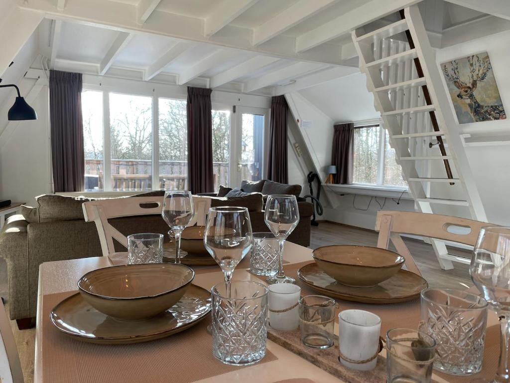 a dining room table with wine glasses and a staircase at ArdennenVakantieBungalow in Durbuy