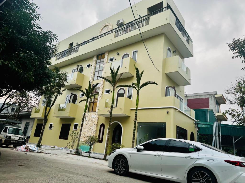 a white car parked in front of a yellow building at Mây Home Hoa Lư in Phúc Trì