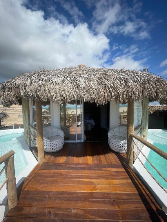 a resort with a thatched roof and a swimming pool at Positano Village in Canoa Quebrada