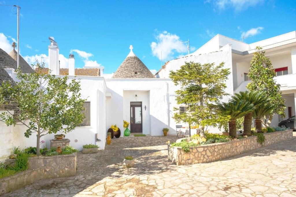 a white house with a courtyard with trees at Il trullo di Memarì in La Correggia