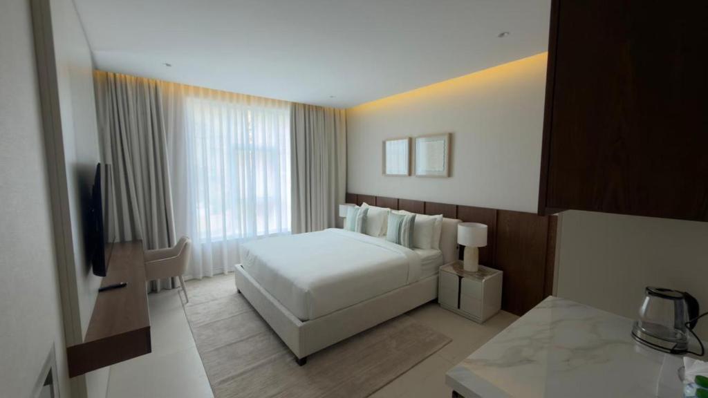 a bedroom with a white bed and a large window at Hatta Residence in Hatta