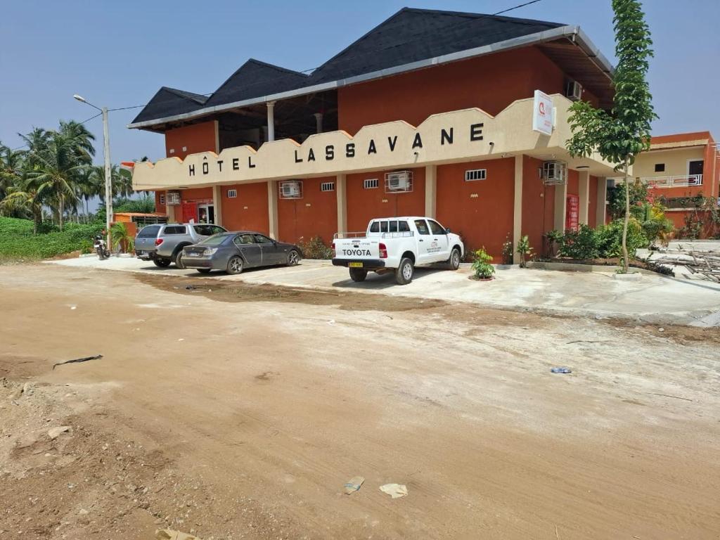 a hotel with cars parked in front of a building at Complexe Hôtelier Lassavane in Jacqueville