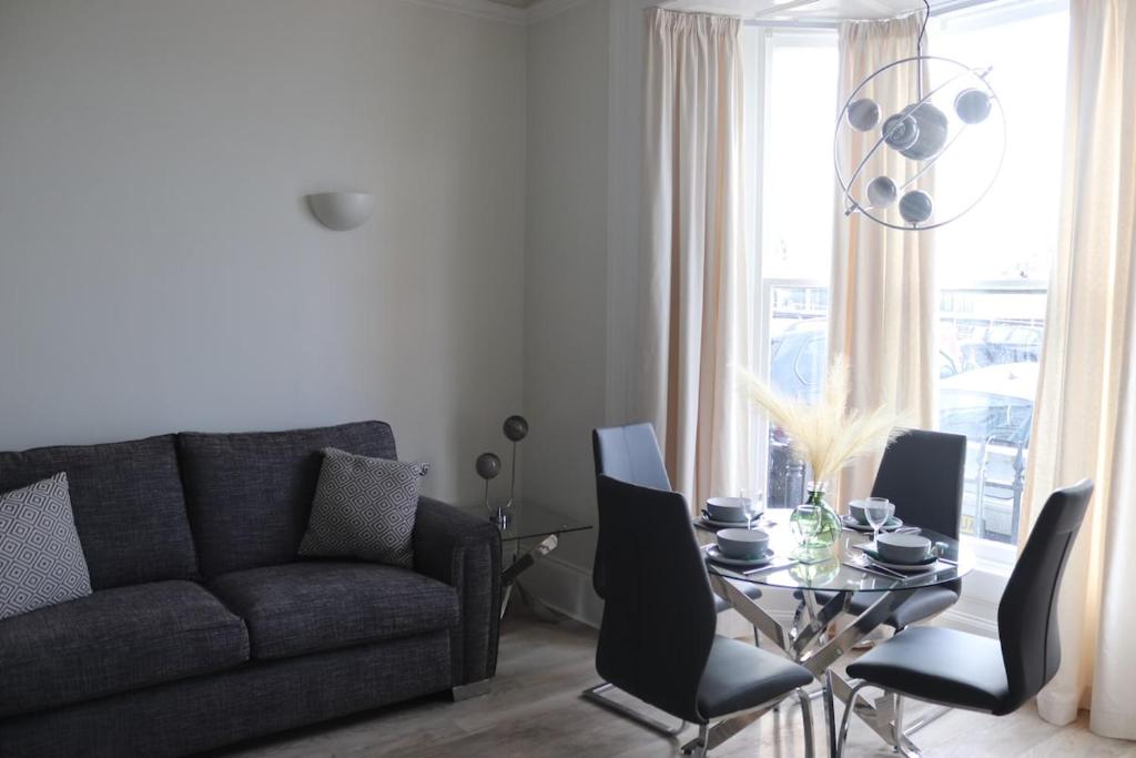 a living room with a couch and a table with chairs at Stunning Seafront Apartment in Aberystwyth