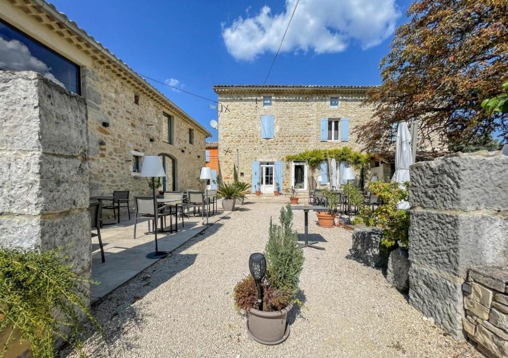 a courtyard of a stone building with tables and chairs at La Bastide de Vallon in Vallon-Pont-dʼArc