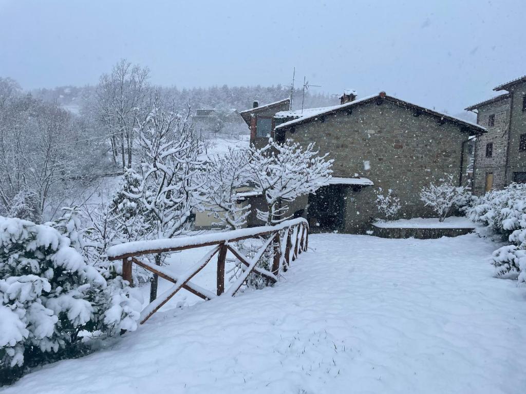 a snow covered yard with a fence and a house at L'Orto di Scarpaccia in Pratovecchio