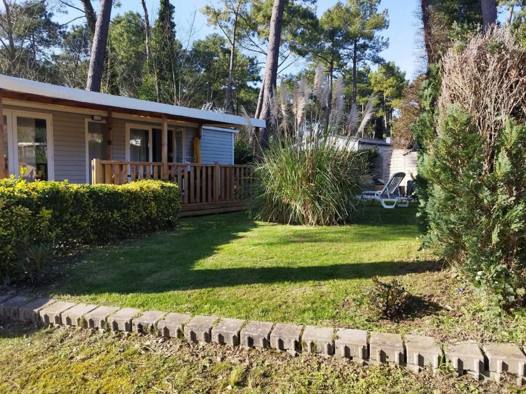 a house with a yard with grass and bushes at La Margotine Mobil Home Cosy Plage et Dunes Camiers in Camiers