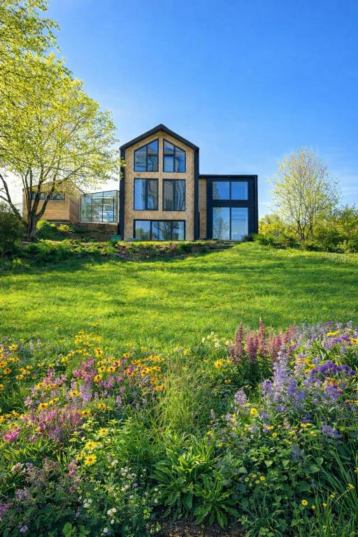 a house on a hill with a field of flowers at Nastawka Cottage Creativity and Regeneration in Raciechowice