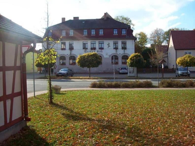 a white building with a red fence in front of a yard at Weißes Roß Crossen in Ahlendorf