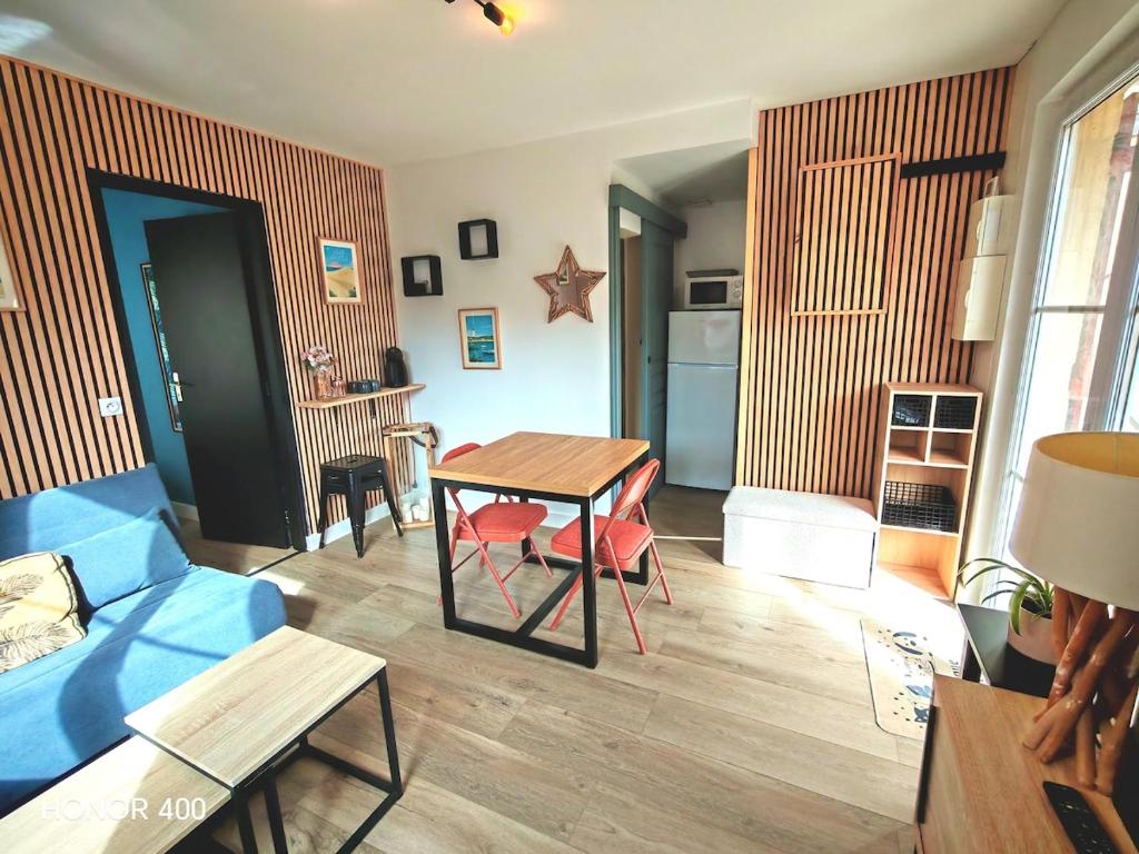 a living room with a table and a blue couch at Appartement à la Hume in Gujan-Mestras