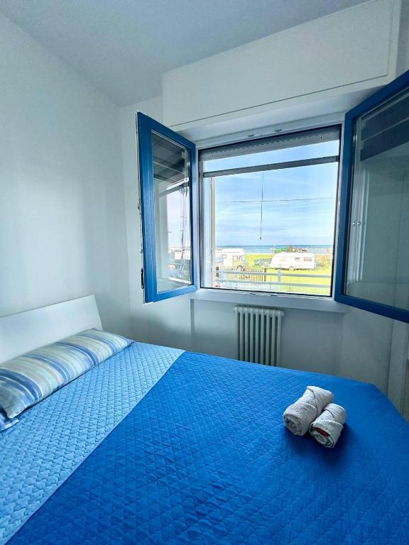 a bedroom with a bed with blue sheets and a window at Mareline Seafront in Fano