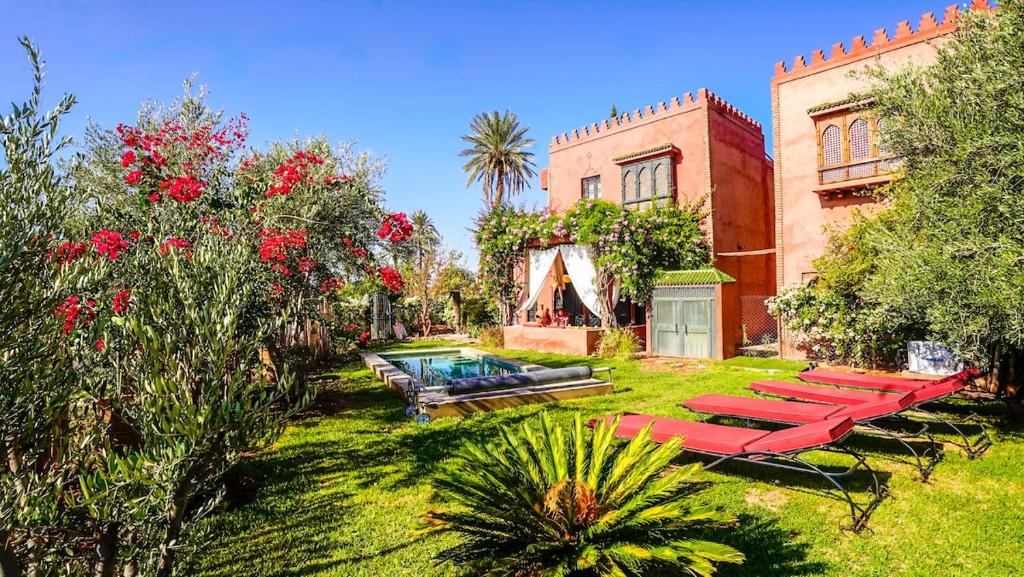 a group of red lounge chairs in a yard at Dar Alba in Marrakesh