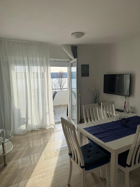 a dining room with a table and chairs and a television at Apartment Perla in Dinjiška