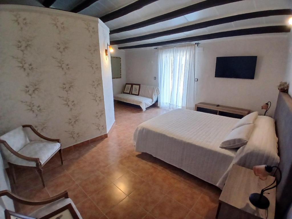 a bedroom with a white bed and a couch at Alojamiento Peña Dorada in Lumpiaque