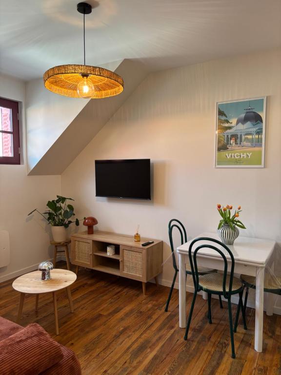 a living room with a table and chairs and a tv at Vichy Cosy T2 plein centre, thermes et parcs in Vichy