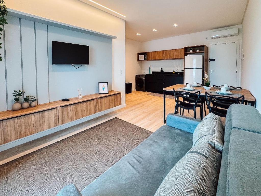 a living room with a couch and a dining room at Flat moderno com churrasqueira próximo à Unifebe in Brusque