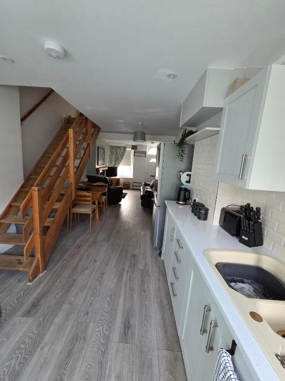 a kitchen with white cabinets and a staircase in a room at Cottage in Sandwith in St Bees