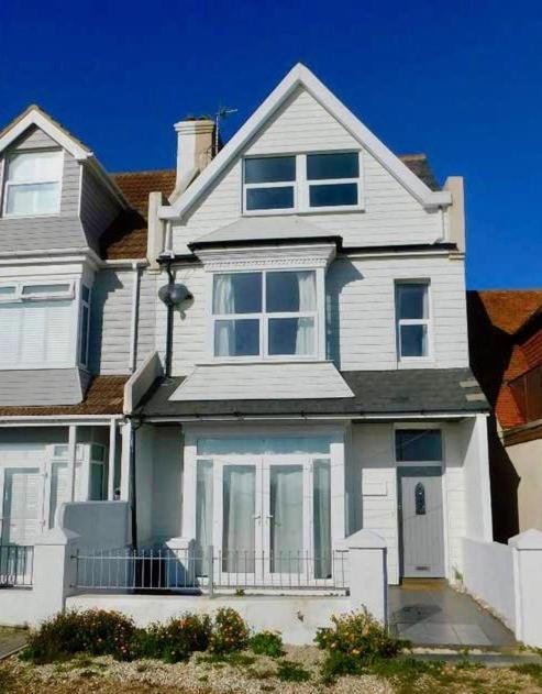 a large white house with a porch at Beautiful 4 Bed Beach House in Pevensey