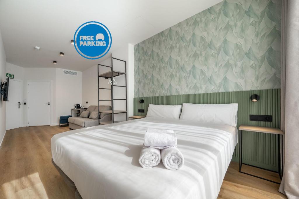 a bedroom with a large white bed with two towels at SÖMN Donostia in San Sebastián