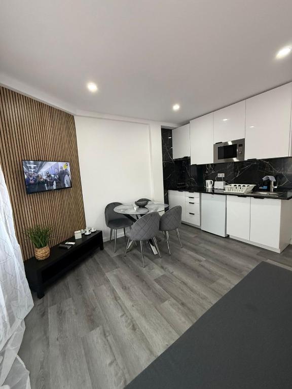 a kitchen with white cabinets and a table and chairs at House Caparica in Costa da Caparica