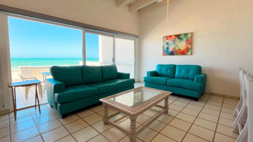 a living room with two blue couches and a table at Charming and Cozy Beachfront Condo - Las Olas II 3 in Puerto Peñasco