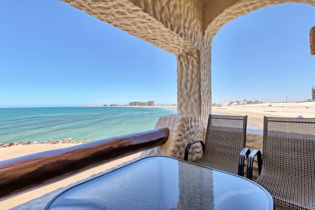 a table and chairs on a beach with the ocean at Unique Oceanfront with Epic Sunsets Pinacate 202 in Puerto Peñasco