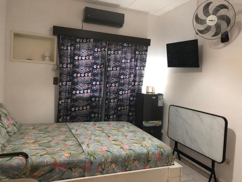a bedroom with a bed in a room with a wall at Chambre indépendante in Port-Gentil