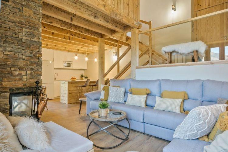 a living room with a blue couch and a fireplace at Eth Estel de Salardú--Casa con vistas de ensueño-Aire Acondicionado-Fibra Optica,5TV- in Salardú