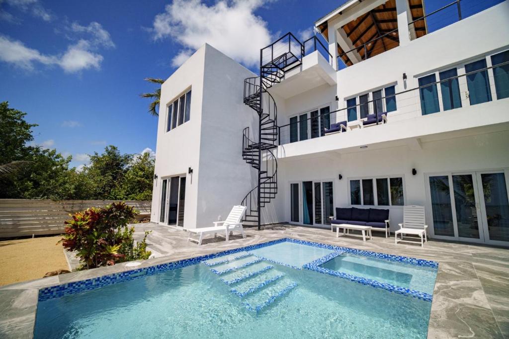 a house with a swimming pool in front of it at Villa Armoniosa Spacious Beachfront 2BR with Pool - Lower Level in Placencia