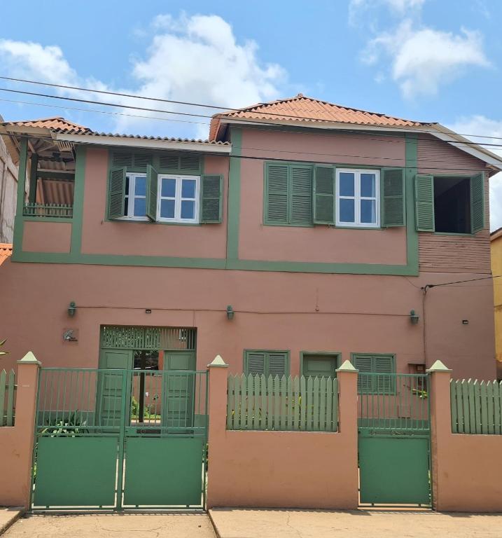 a pink house with a green fence at Chalé Quitxiba in São Tomé