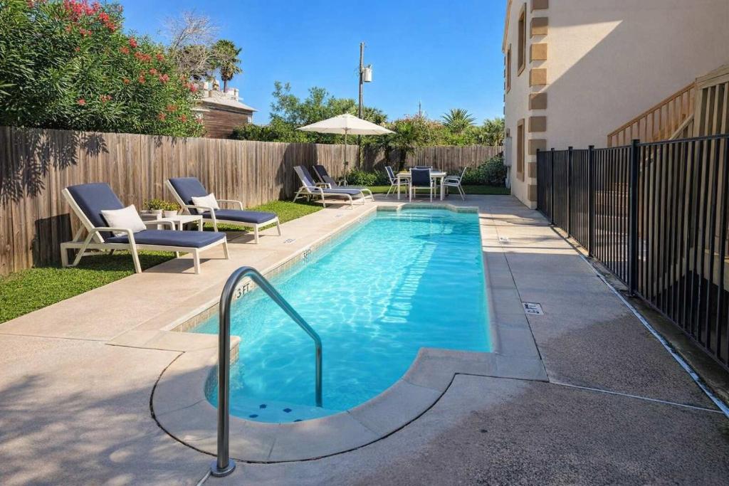 a swimming pool in a yard with chairs and an umbrella at Swanky 2 Bedroom, Easy Walk to Beach Mar y Sol II # 1 in South Padre Island