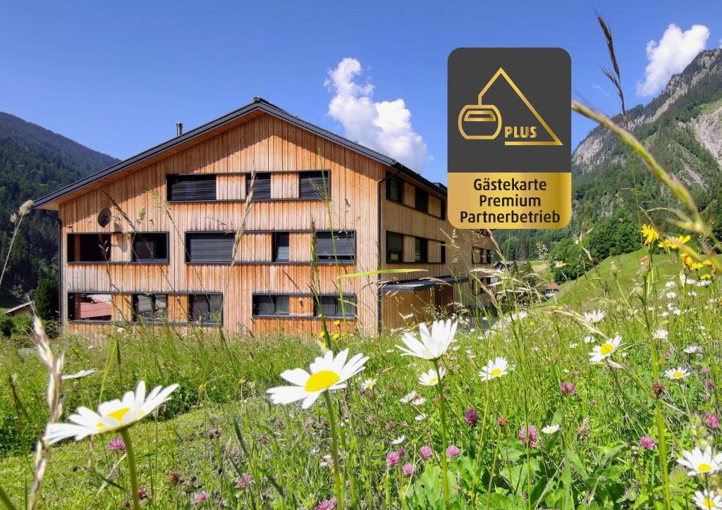 a building in a field with flowers in front of it at Verwall Apartment Arlberg - mit Sauna, Balkon und Skiraum in Wald am Arlberg